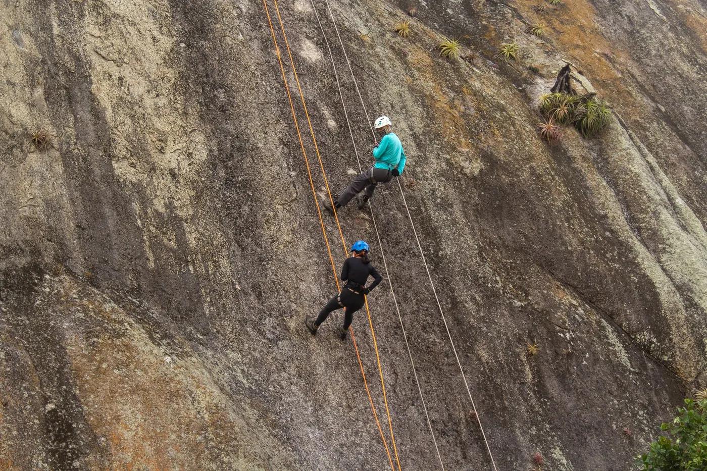 Two climbers scale a rugged granite cliff with ropes, showcasing strength and teamwork.