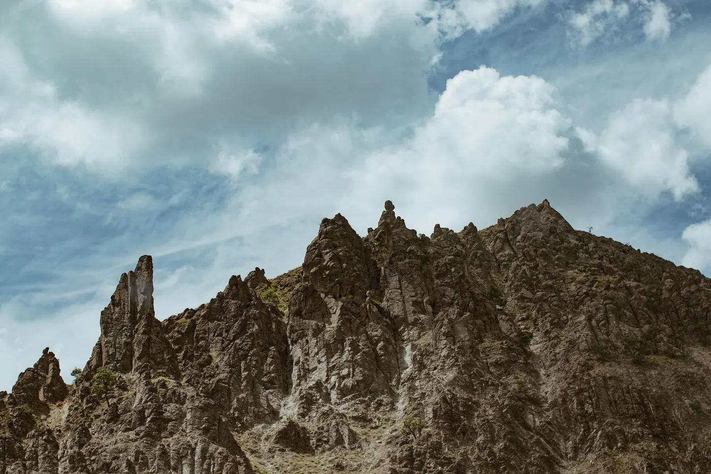 A scenic view of jagged rocky mountain peaks under a cloudy sky, capturing the raw beauty of nature.