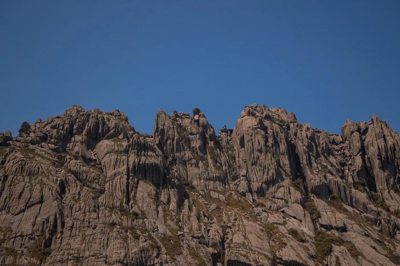 Stunning rugged mountain peaks silhouetted against a clear blue sky, displaying natural rock formations.