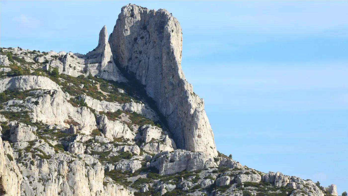 Imposing vertical rock formation with clear blue sky, perfect for nature photography enthusiasts.