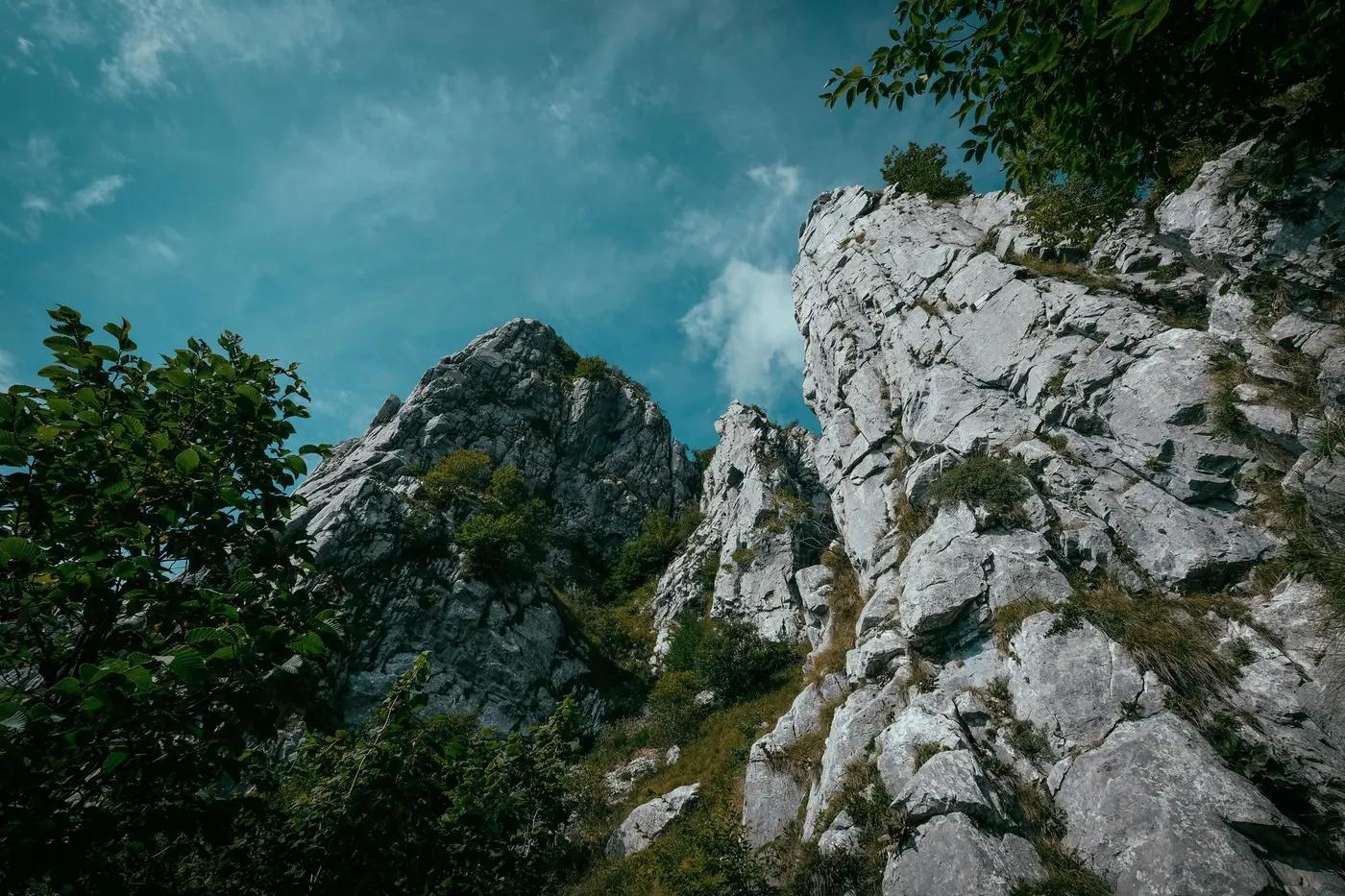 Captivating view of rugged rocky formations with lush greenery under a clear blue sky, perfect for nature enthusiasts.