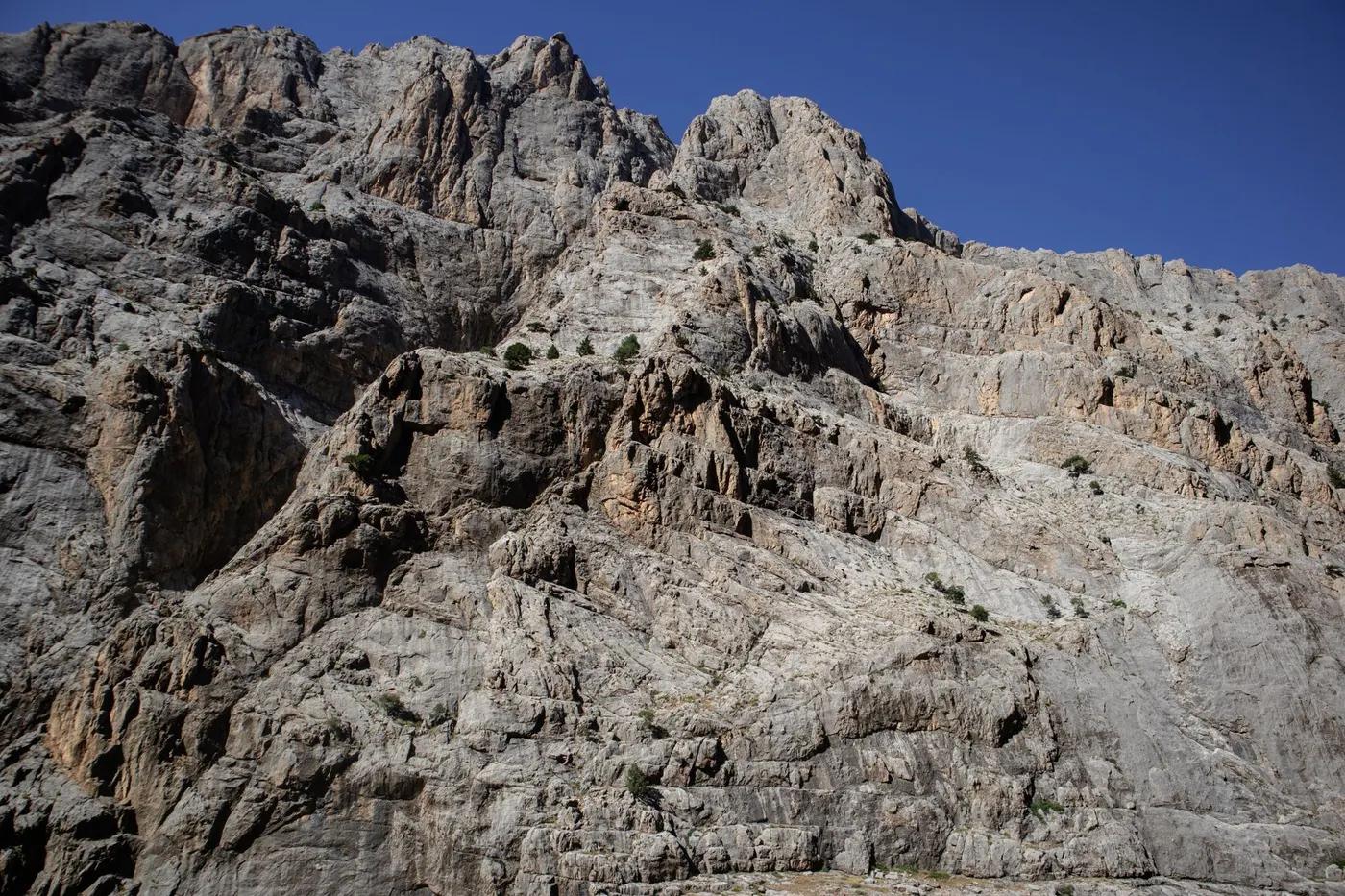 Stunning rock formations of a mountain under clear summer sky, ideal for travel and nature themes.