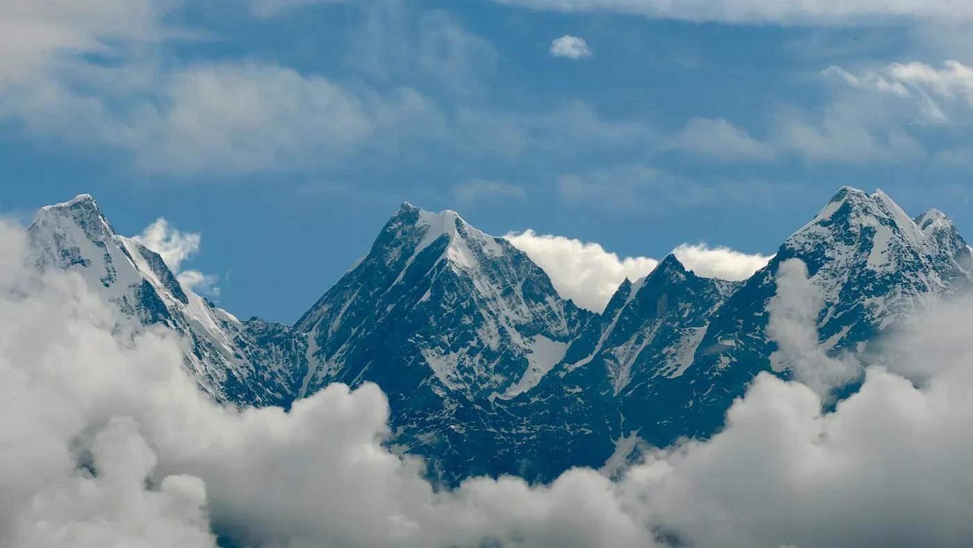 Snow-capped Himalayan peaks surrounded by clouds in Munsyari, India.