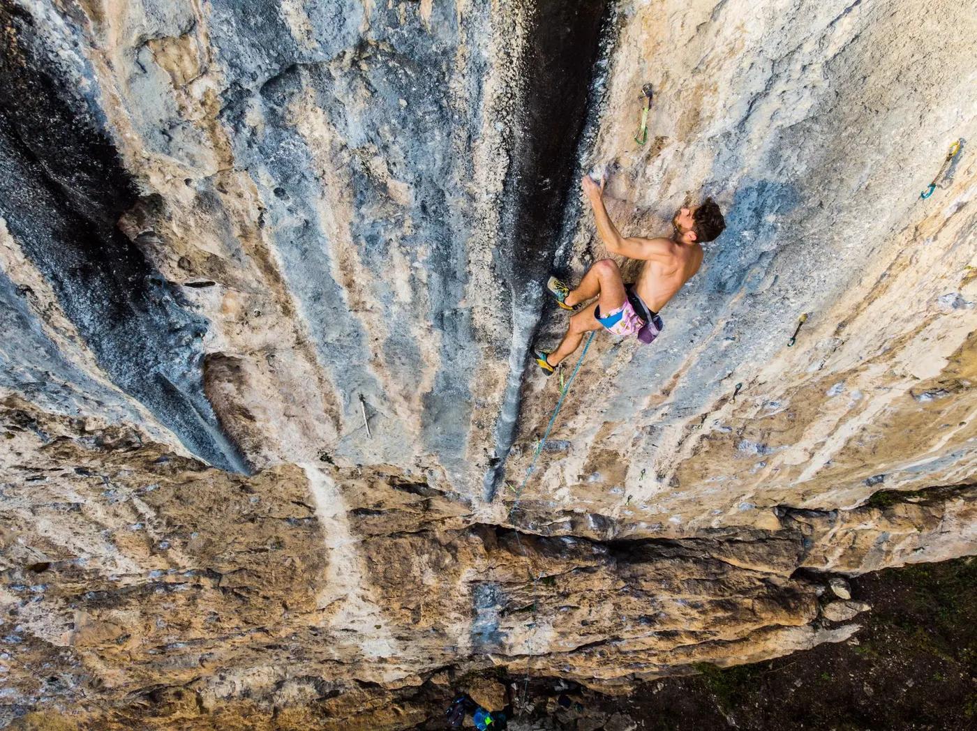 A rock climber demonstrates skill and bravery scaling a steep limestone wall in Italy.