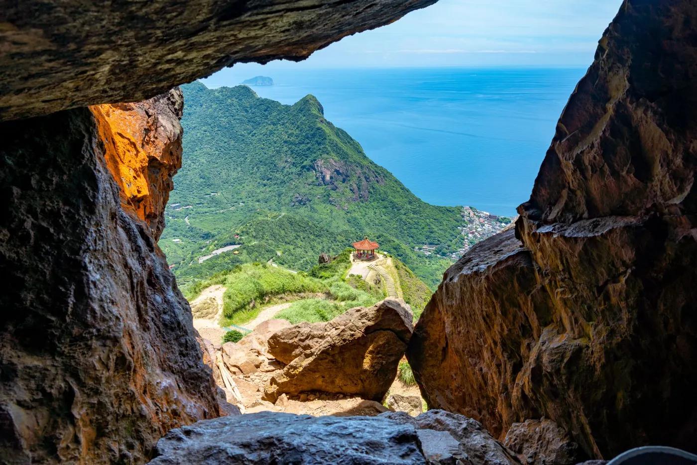 Explore the breathtaking view from a cave overlooking lush hills and the coastline in New Taipei City, Taiwan.