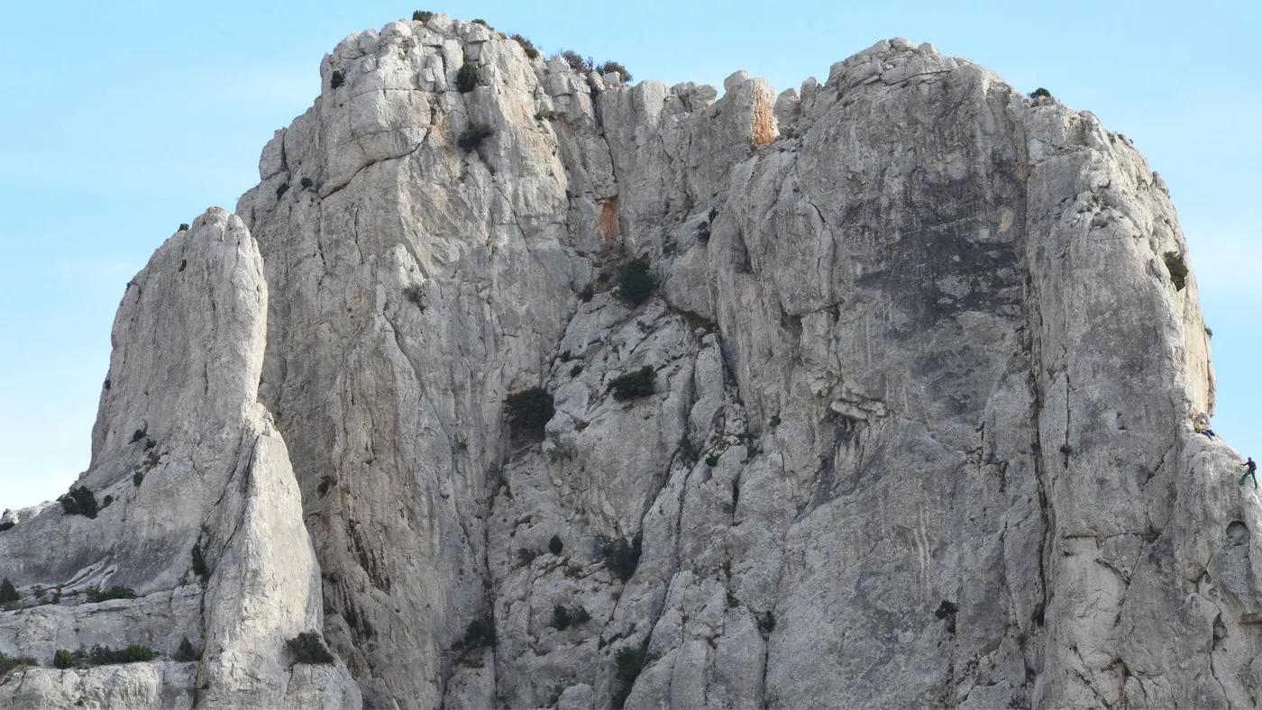 Stunning vertical view of a rocky mountain cliff with a clear blue sky backdrop.