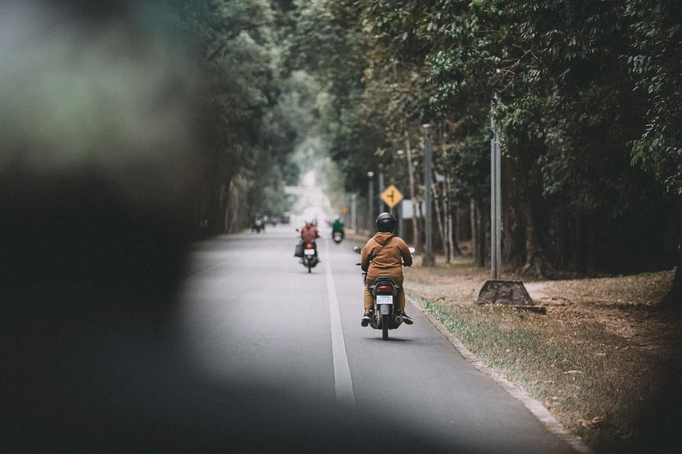 Motorcyclists journey through a scenic forest road in Siem Reap, Cambodia, showcasing adventure and exploration.