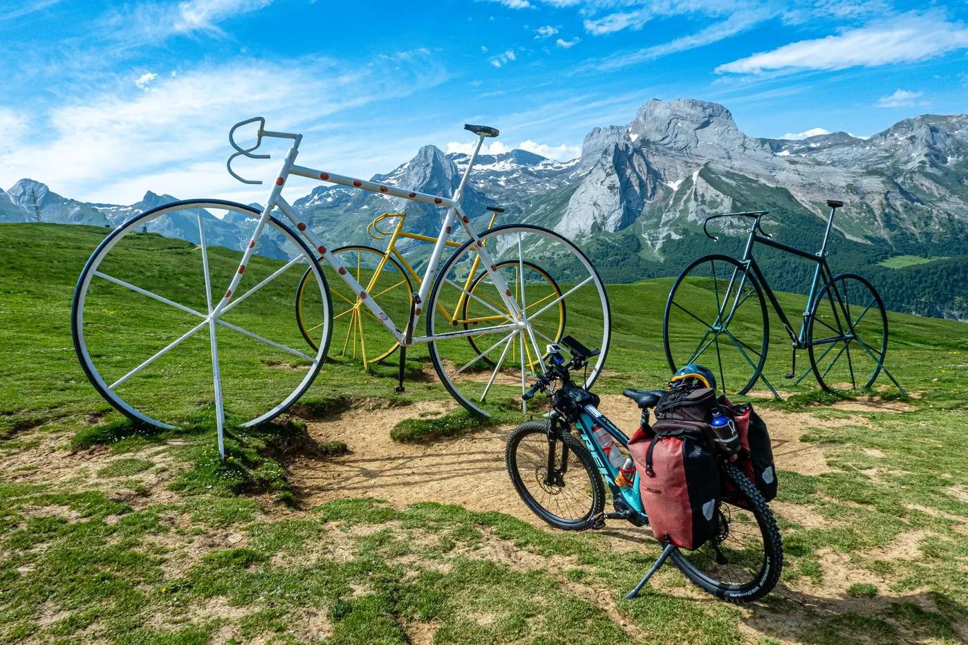 Colorful bicycle sculptures with a stunning mountain backdrop under a vibrant blue sky.