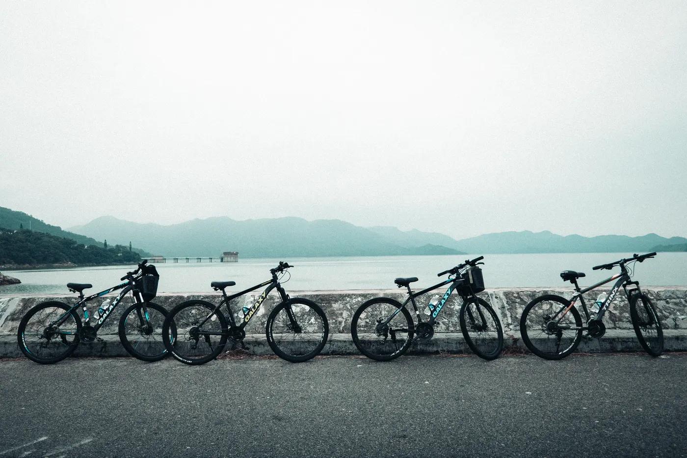 Five mountain bikes lined up by a peaceful lake in New Territories, Hong Kong.