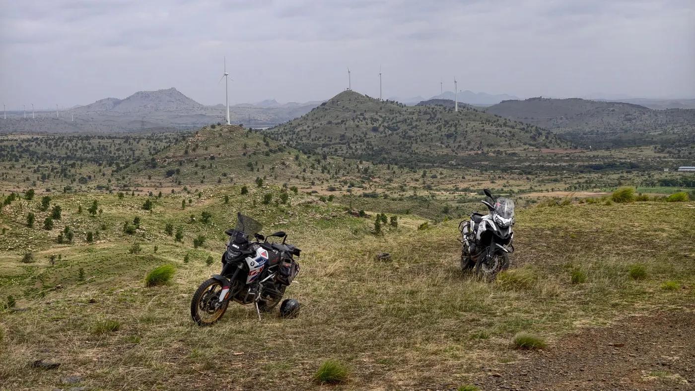 Explore the rugged beauty of Penukonda, India with adventure motorcycles amidst rolling hills and wind farms.