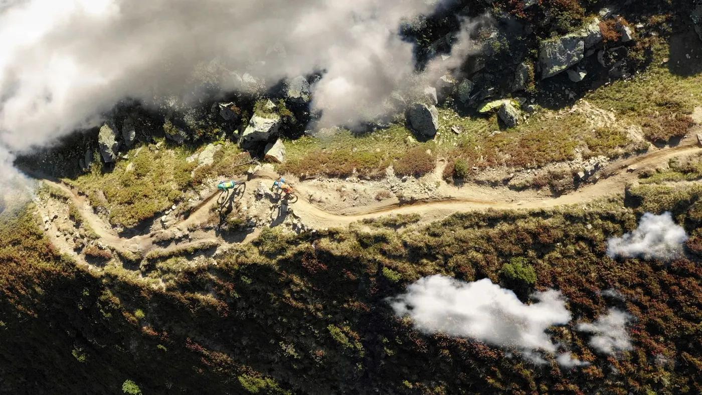 Drone shot of cyclists biking on a scenic mountain trail in Davos, Switzerland.