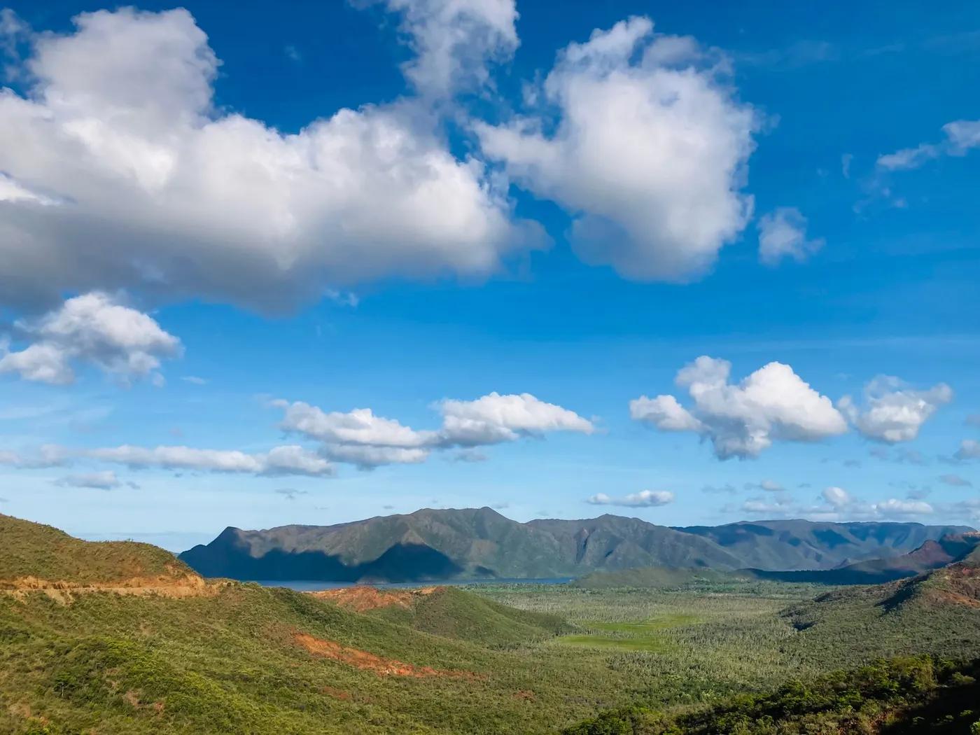 Breathtaking view of mountains and clouds in New Caledonia with clear blue sky.