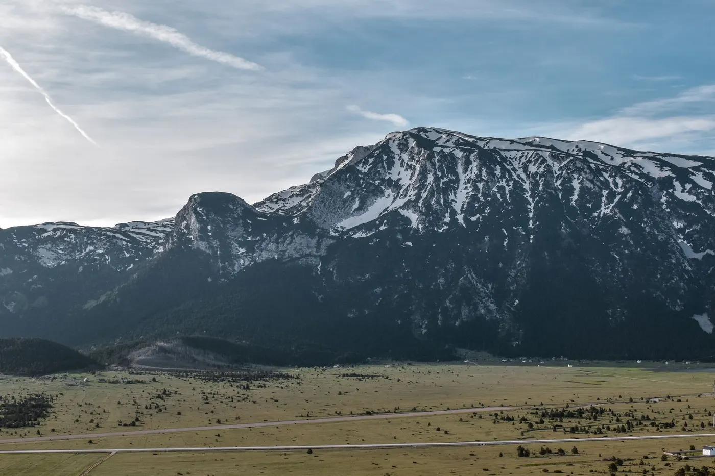 Explore the breathtaking view of snowcapped mountains and expansive fields in Bosnia.