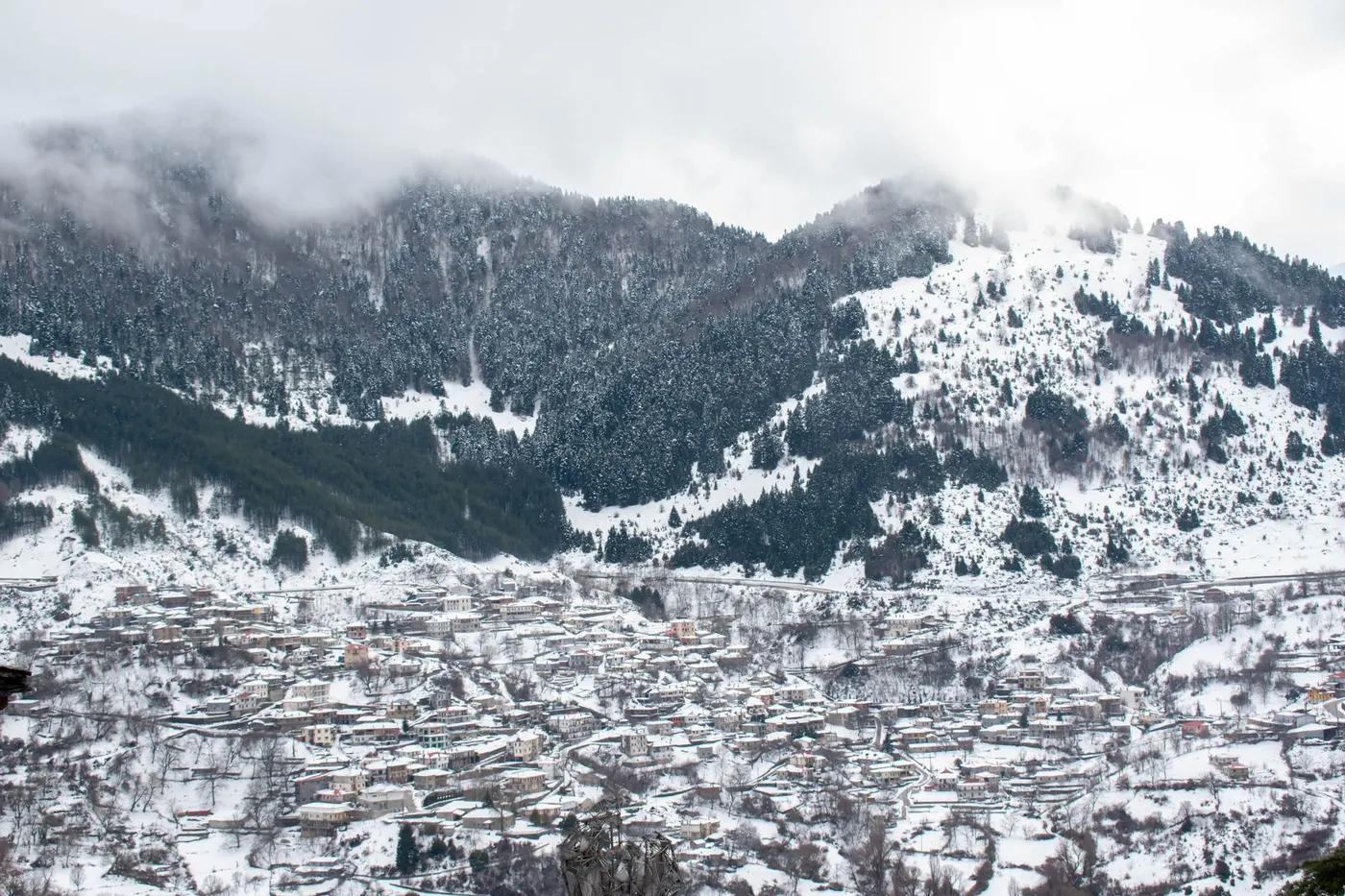 Charming winter landscape of Metsovo, Greece, with snow-covered mountains and village.
