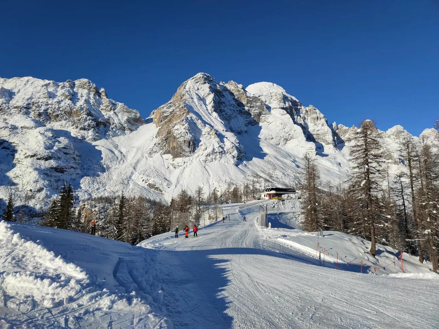 Skiers enjoying a sunny day at a snow-covered resort in the Italian Alps.