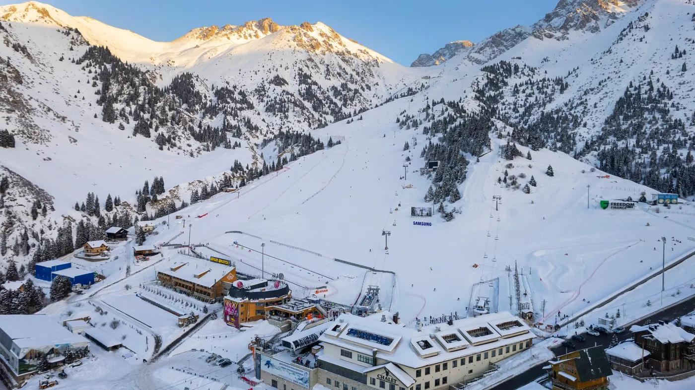 Aerial view of a ski resort in Almaty, Kazakhstan with snowy mountains and clear skies.