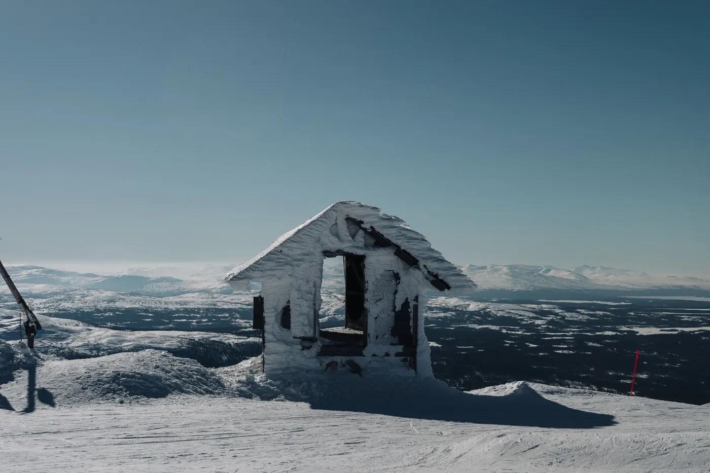 Remote snow-covered hut on a winter mountain landscape with panoramic views.