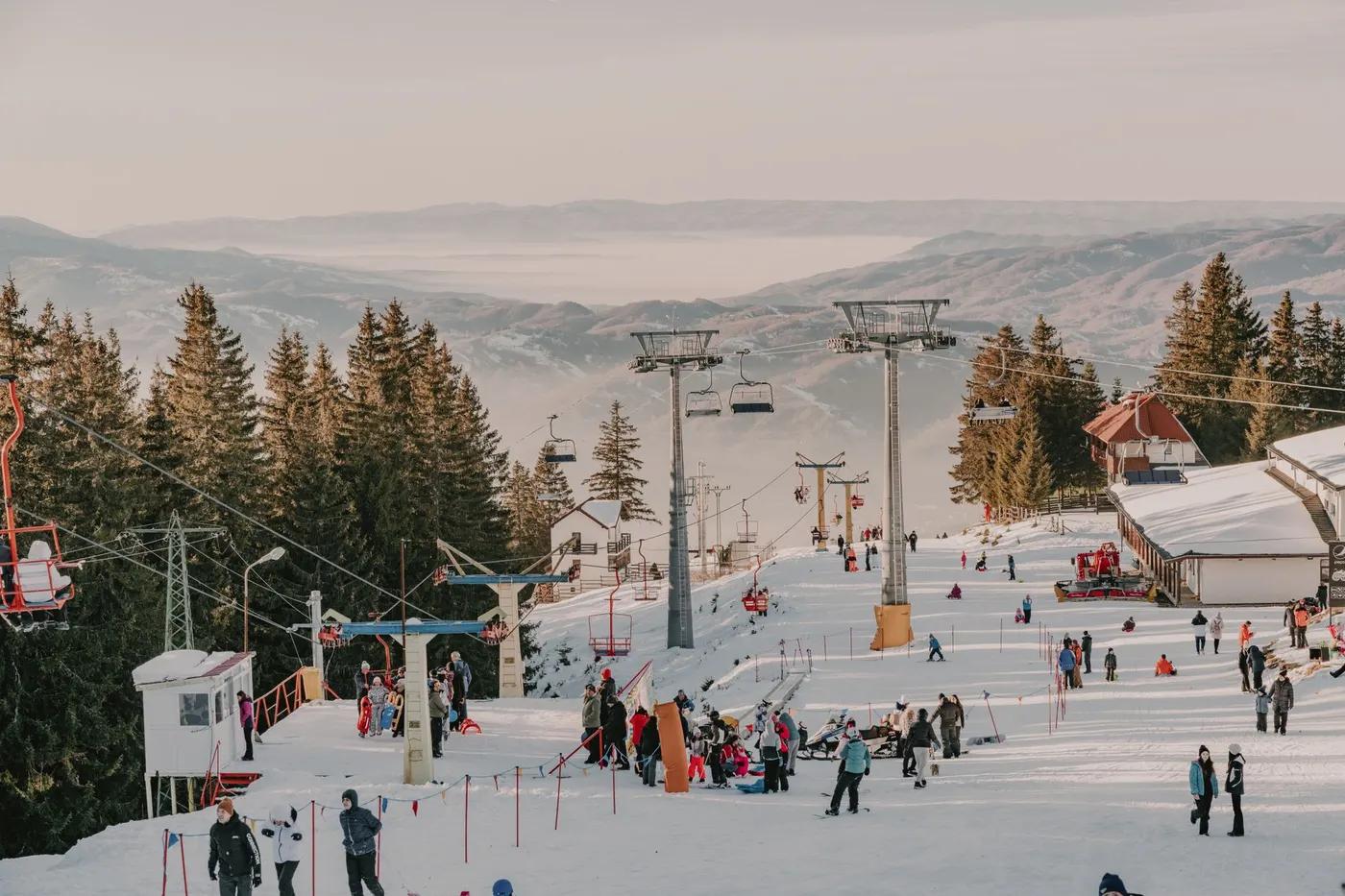 Winter activities at a ski resort in Romania's Parâng Mountains with snowy slopes.