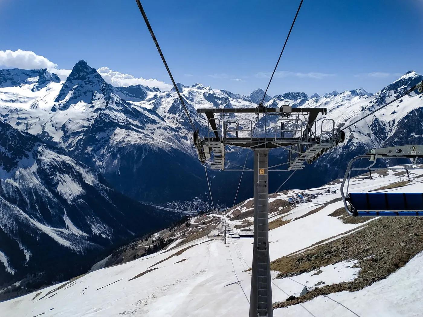 A stunning view of snowy mountains and ski lift in Dombay, Russia, showcasing winter beauty.