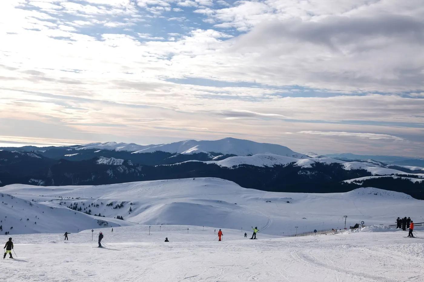 Captivating snowy mountain panorama with skiers in Sinaia, Romania.