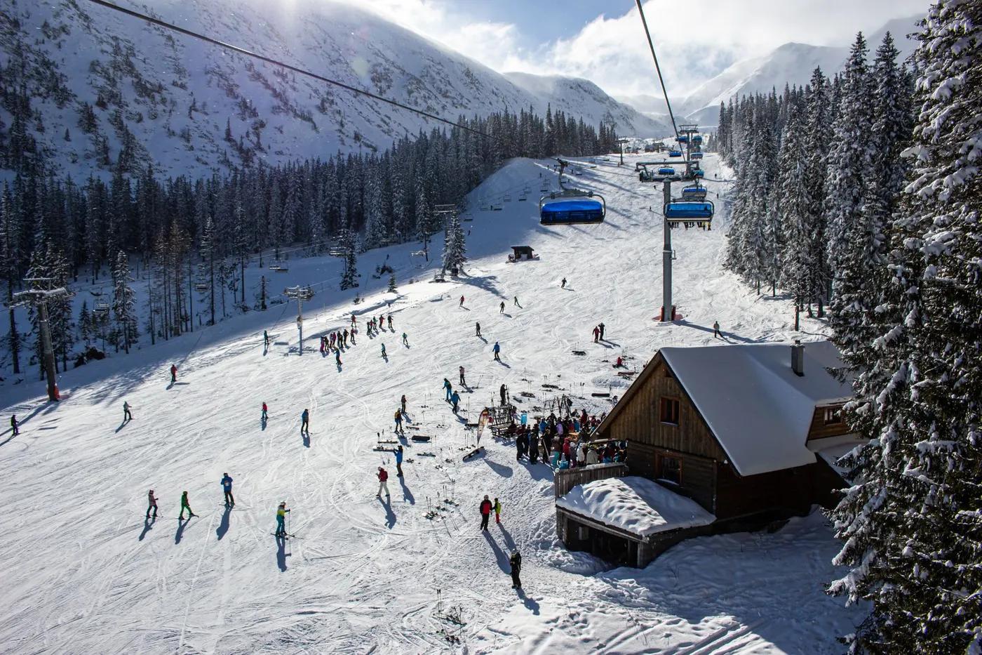 A vibrant ski resort scene in Zuberec, Slovakia, showcasing skiers and snowy slopes.