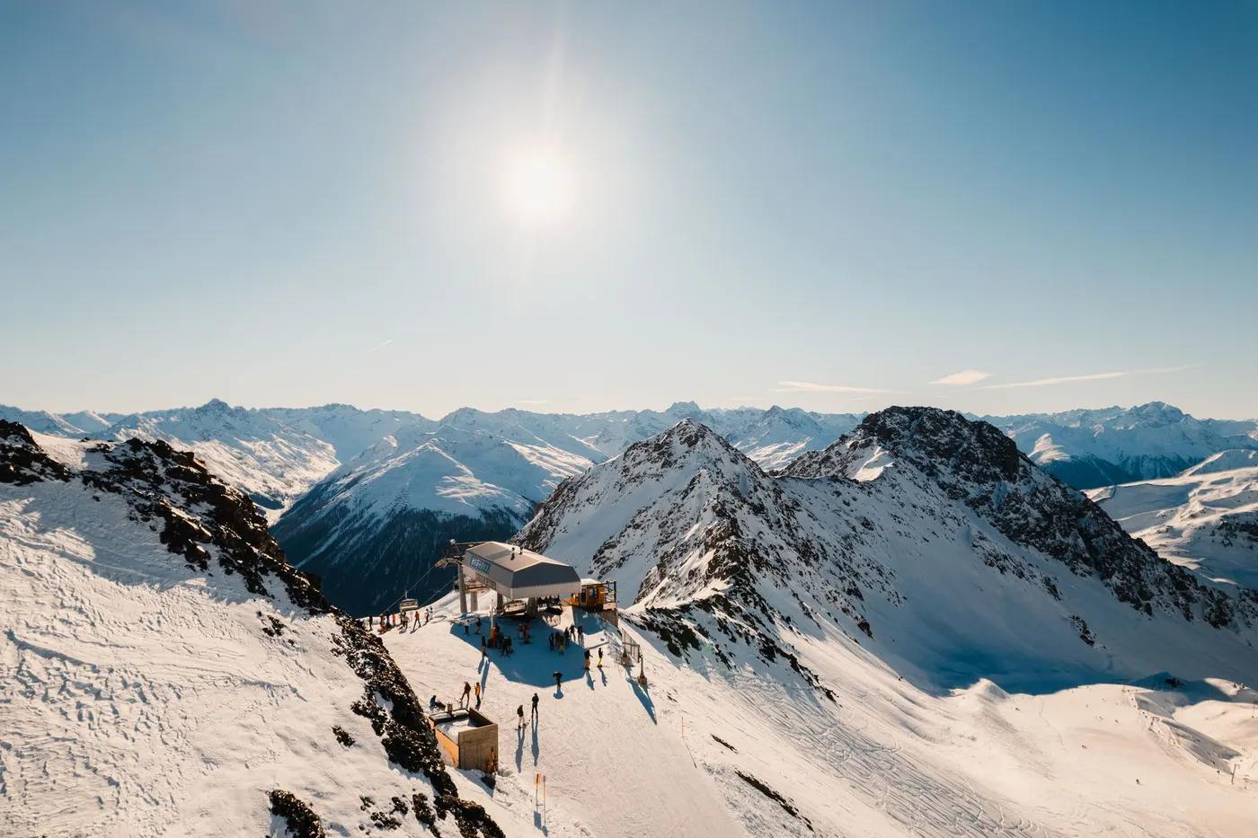 Beautiful snowy mountain landscape at Klosters, Switzerland, with a ski lift bathed in winter sunlight.
