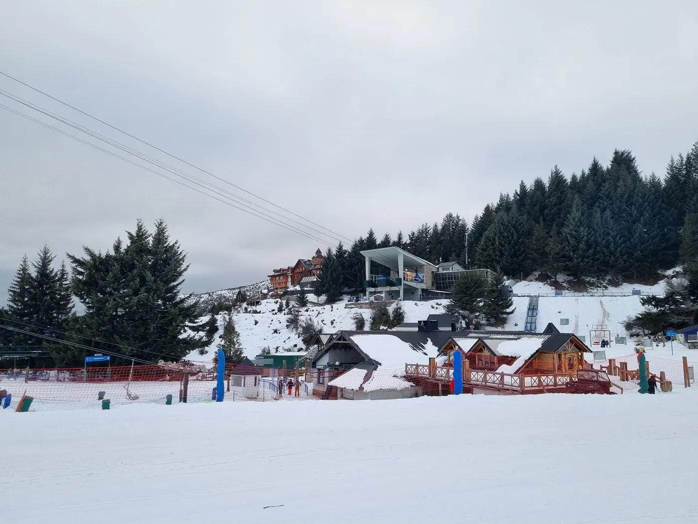 Scenic winter view of a ski resort with cabins and snowy terrain.