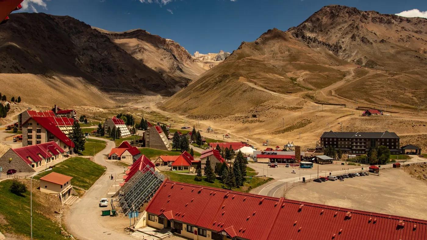 Small settlement with modern red roofed cottages located near mountains against blue sky on sunny day