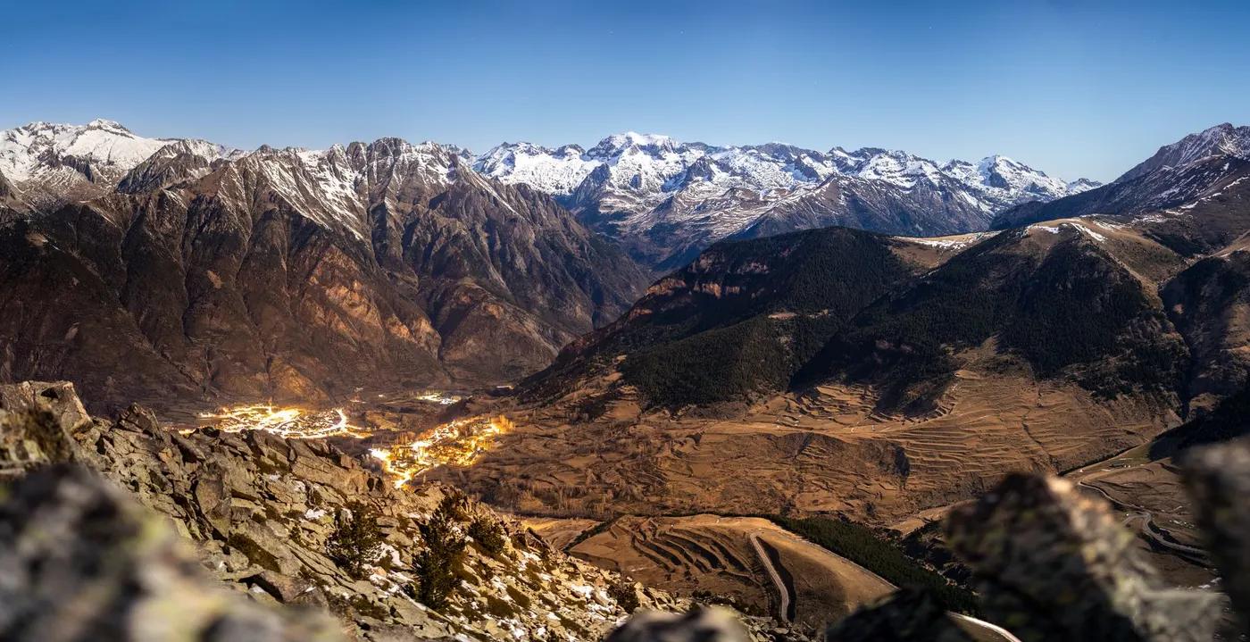 A breathtaking view of the Pyrenees mountains at night with illuminated villages in the valley below.