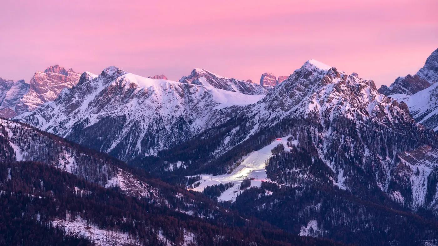Stunning panoramic view of snow-covered Alps during sunset, showcasing serene winter beauty.
