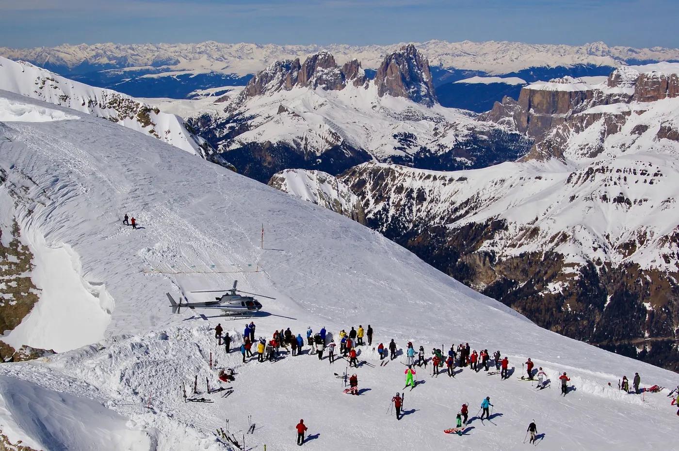 A stunning winter scene of skiers and helicopter on the Dolomites in Italy.