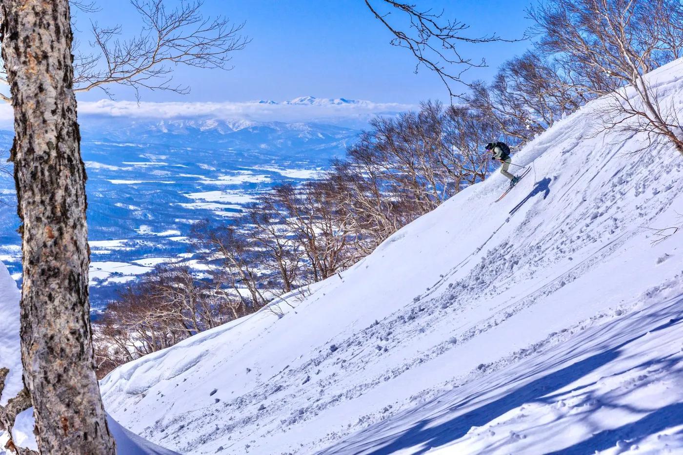 Skier navigating a steep snow-covered slope with a breathtaking mountain view in the background.