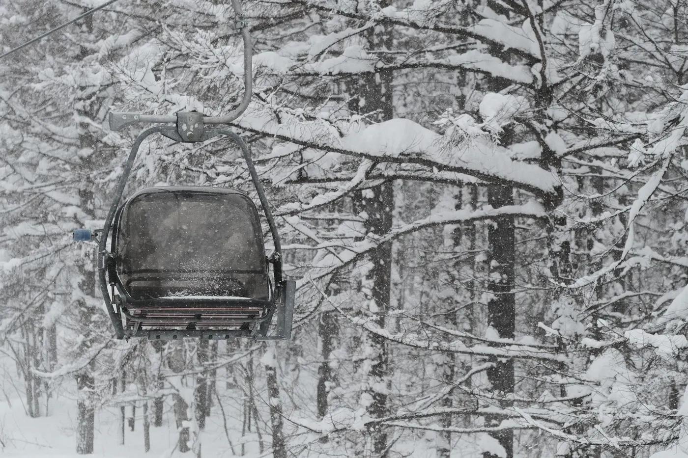 Empty ski lift in a snowy Japanese forest, capturing the serene winter landscape.