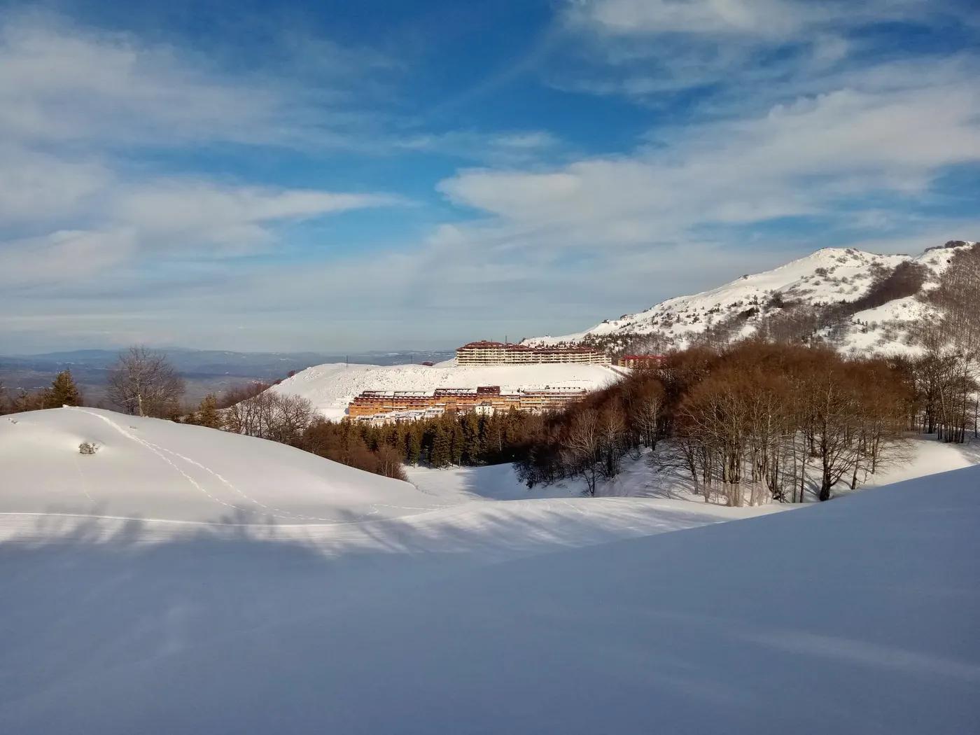 Captivating landscape of Campitello Matese in winter with snow-covered mountains and clear blue skies.