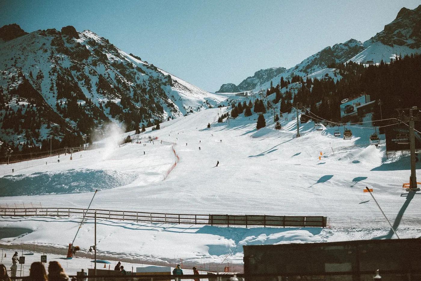 Scenic view of a ski resort in Almaty, Kazakhstan with snowy mountains and skiers.