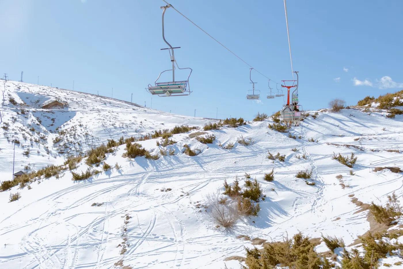 Ski lift over snow-covered slopes in Mavrovo, North Macedonia, under a clear blue sky.