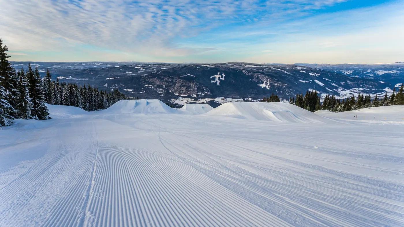 Snowy ski slope with stunning mountainous views under a clear winter sky, perfect for a ski adventure.