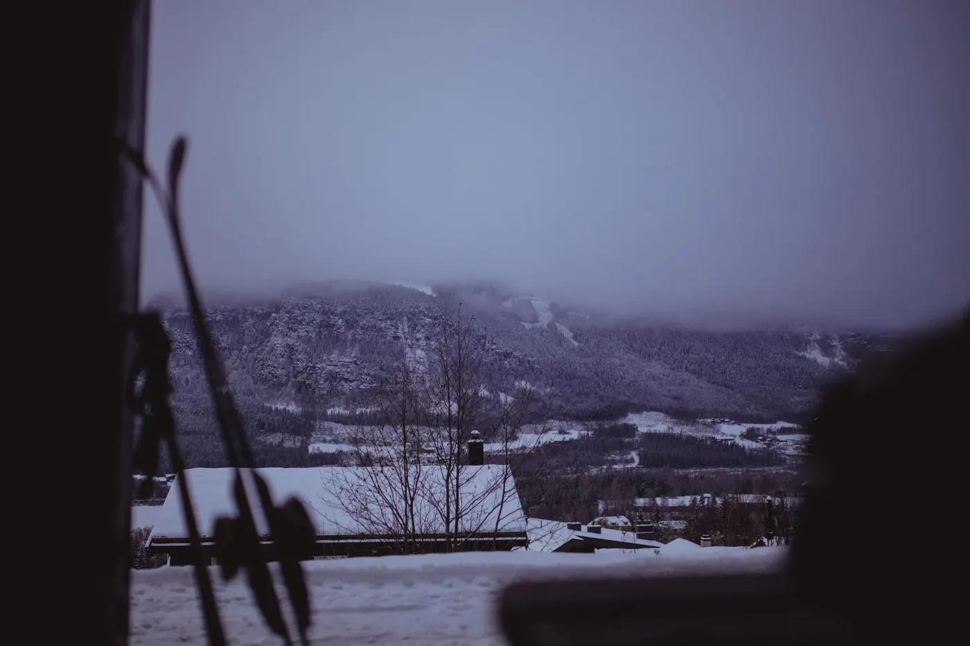 Tranquil winter scene of snow-covered mountains and fog in Hafjell, Norway.