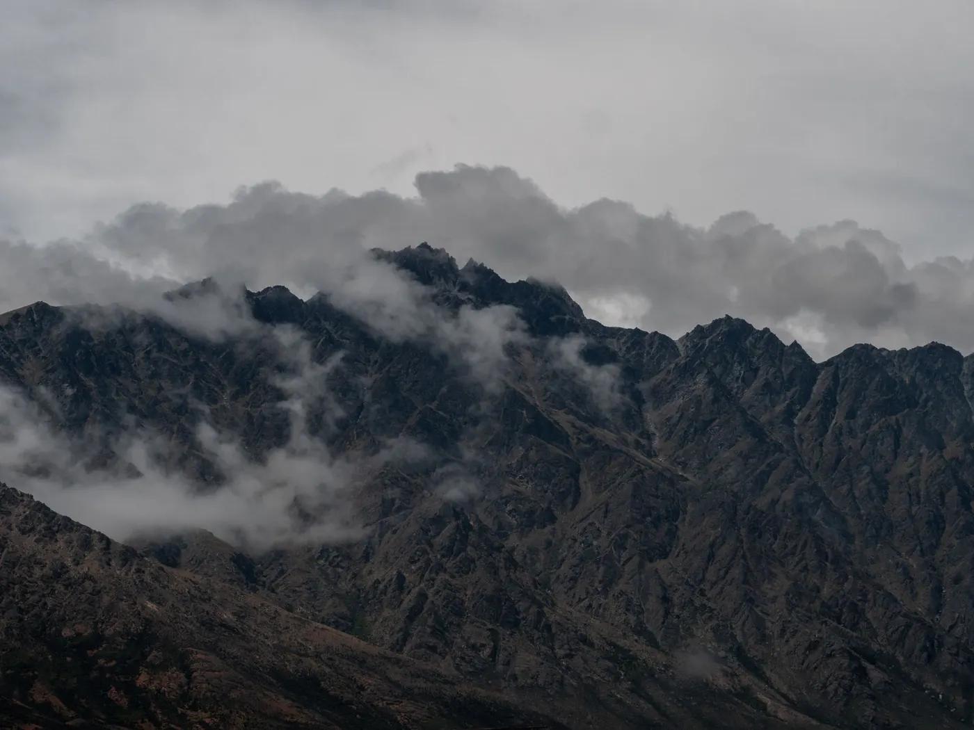 Captivating view of the Remarkables mountain range under dramatic clouds in Queenstown, New Zealand.