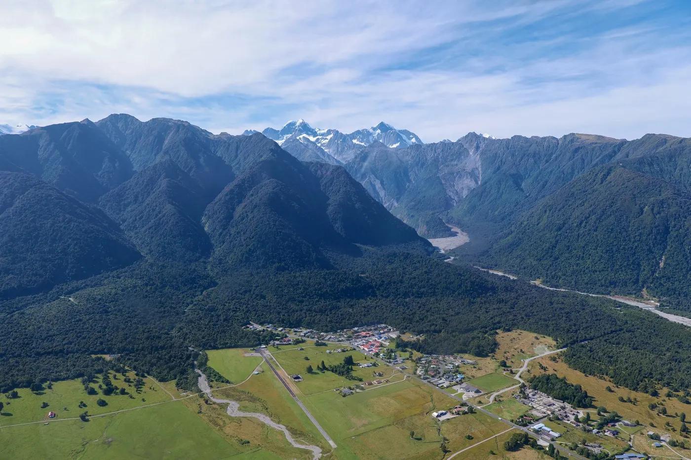Stunning aerial shot of Fox Glacier Village with breathtaking mountain backdrop in New Zealand.
