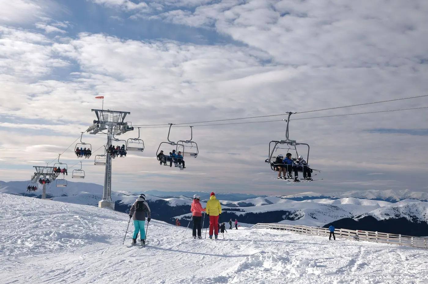 A scenic view of skiers and ski lifts on snowy mountains in Sinaia, Romania.