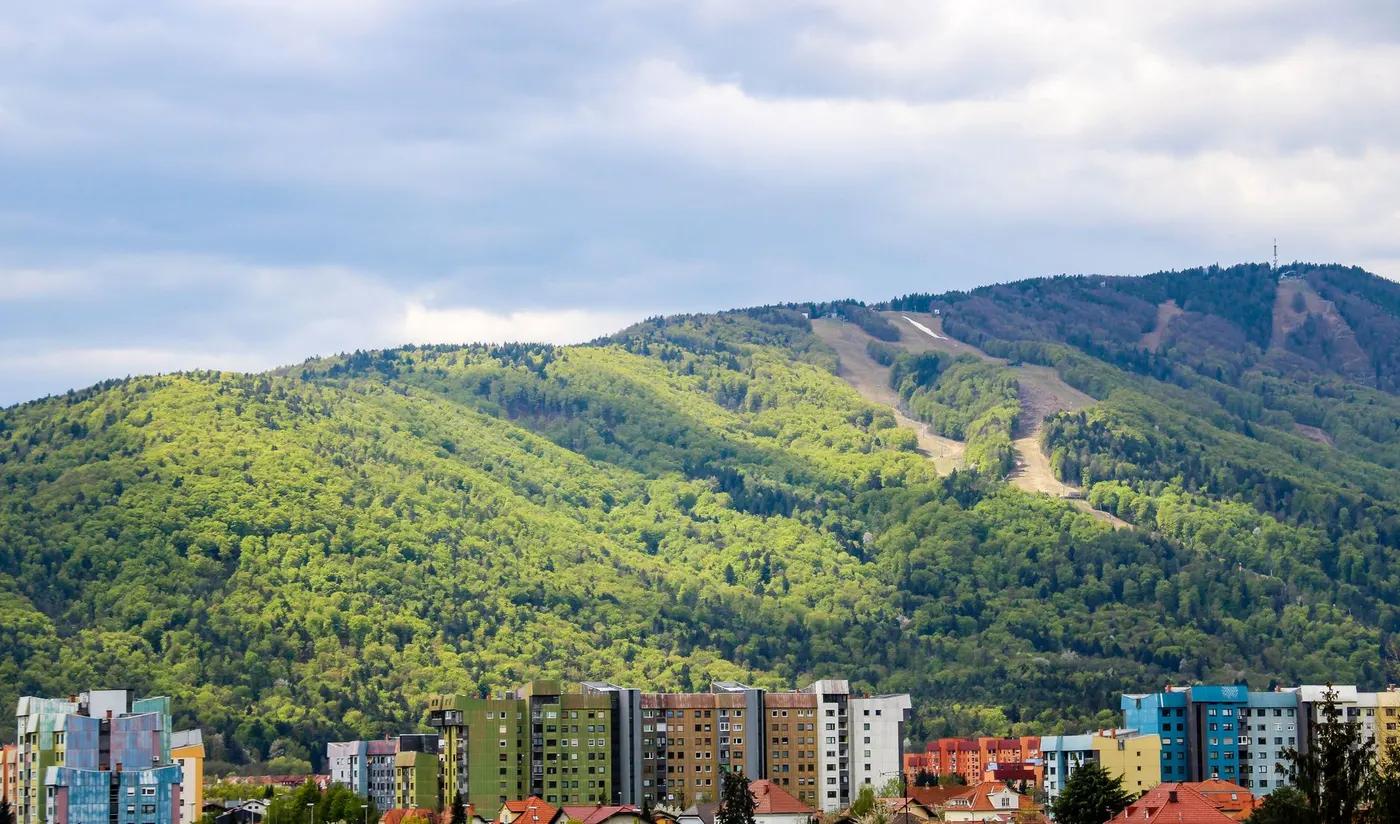 Panoramic view of the lush Pohorje Mountains behind colorful residential buildings in Maribor, Slovenia.