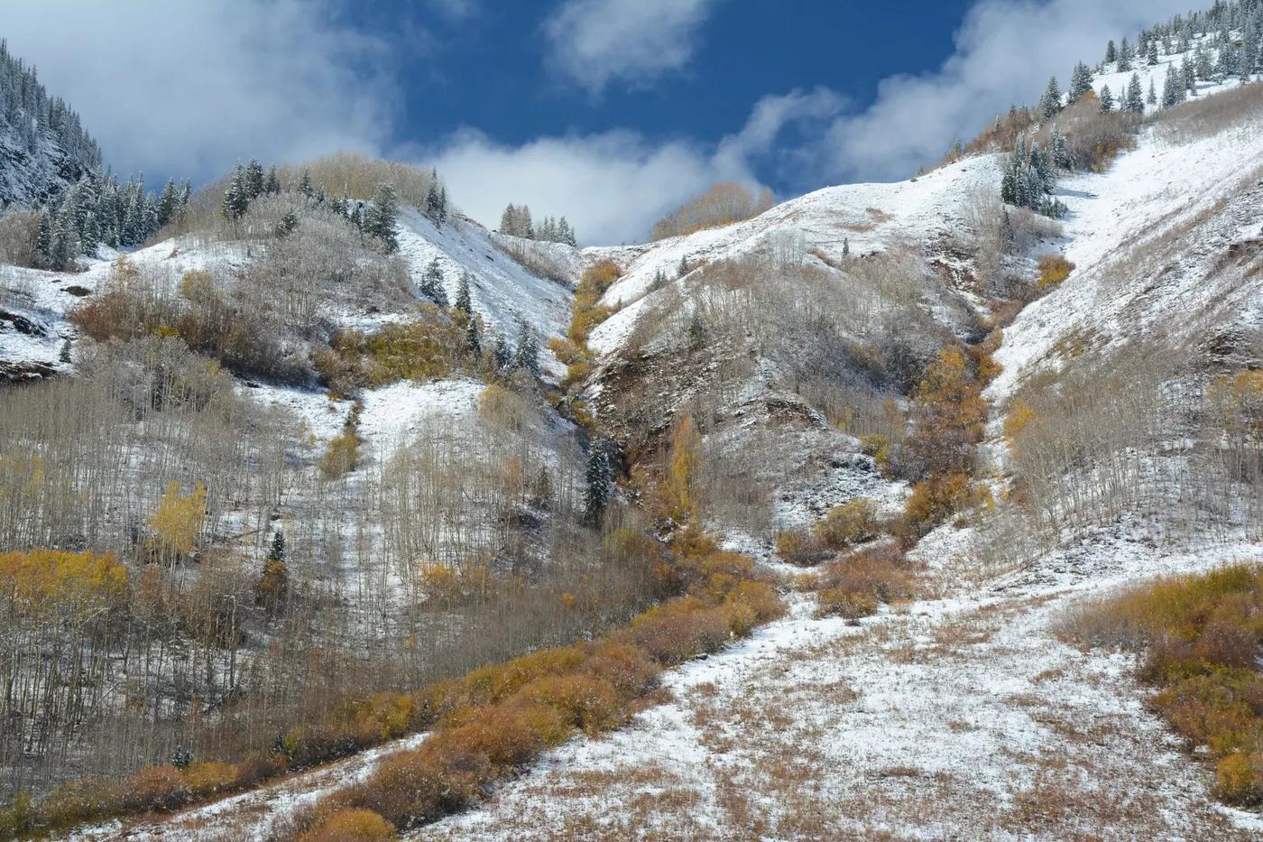 Breathtaking view of Aspen's rugged mountains with autumn foliage and early snow.
