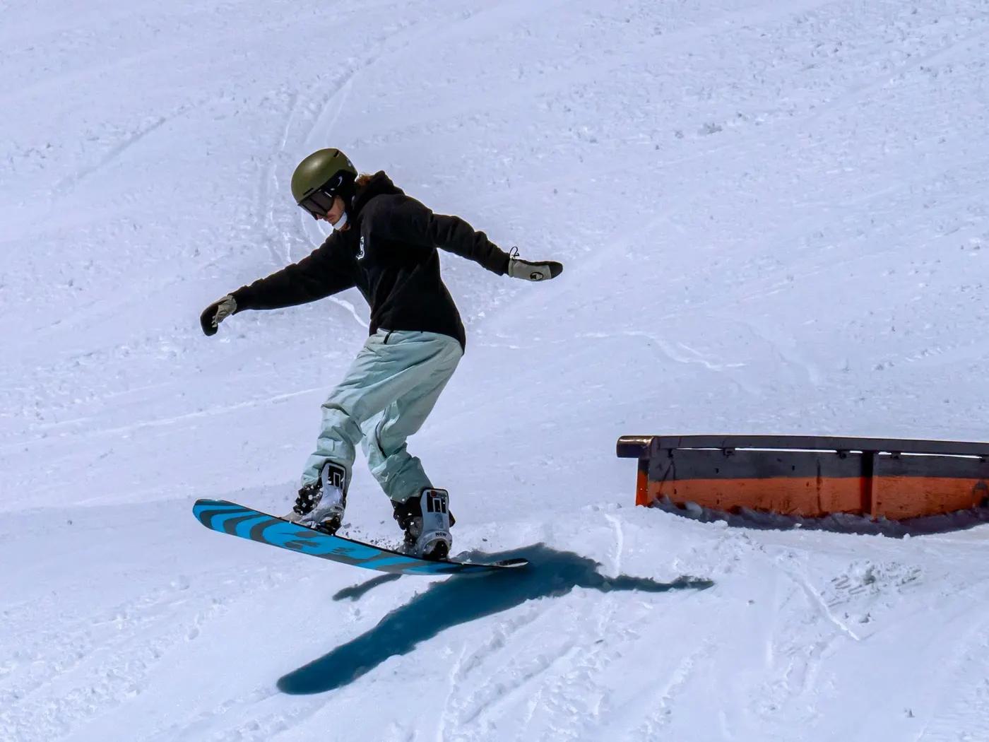 A snowboarder performs a jump on a snow-covered slope, showcasing exciting winter sports action.