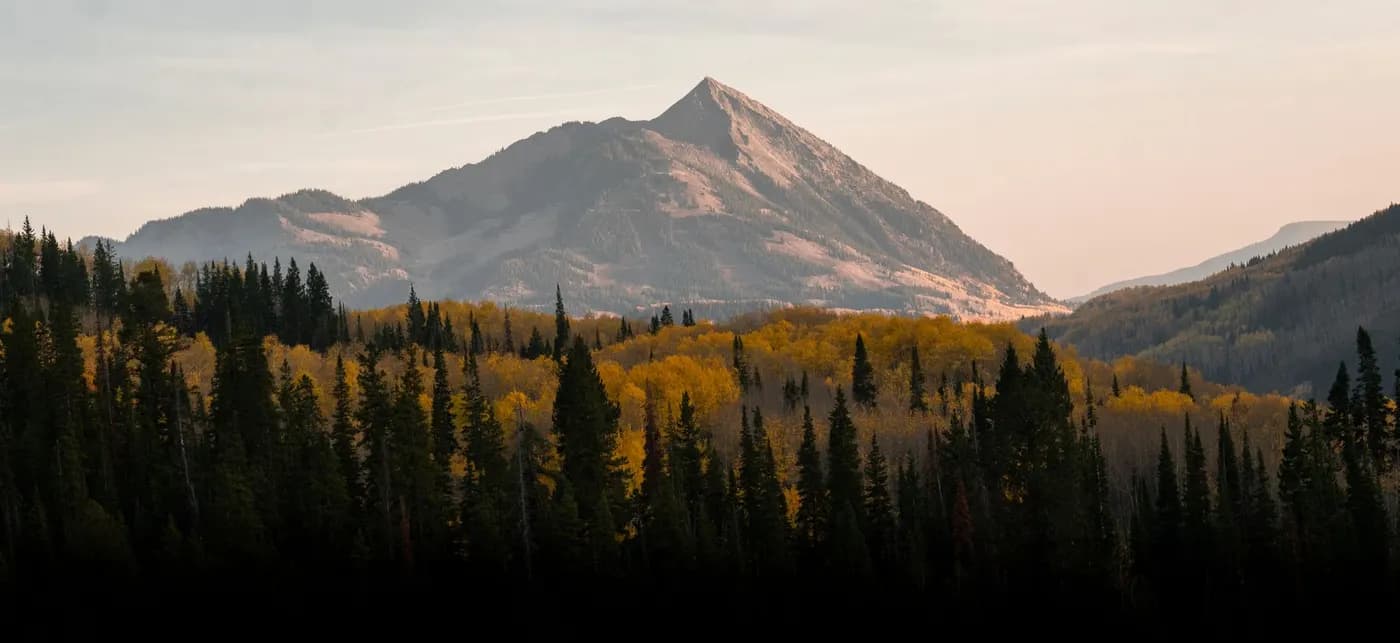 Stunning autumn landscape of Mount Crested Butte with vibrant yellow and green trees.