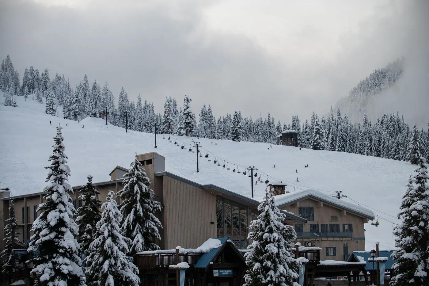 Scenic view of a snow-covered ski resort with skiers on the slope at Snoqualmie Pass.