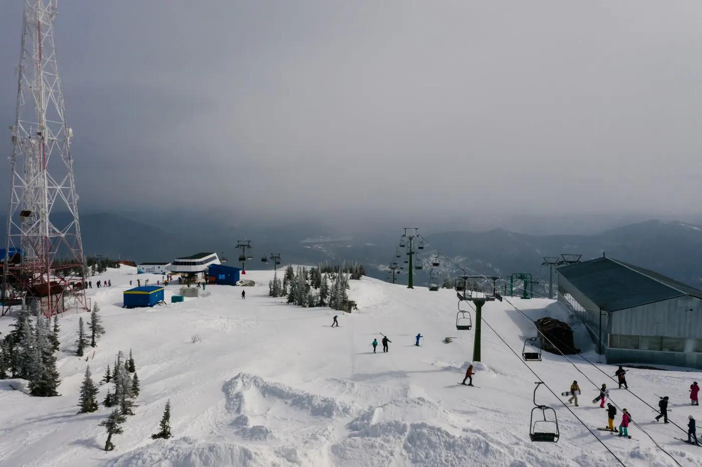 A snowy ski resort scene with skiers and a chairlift under a cloudy winter sky.