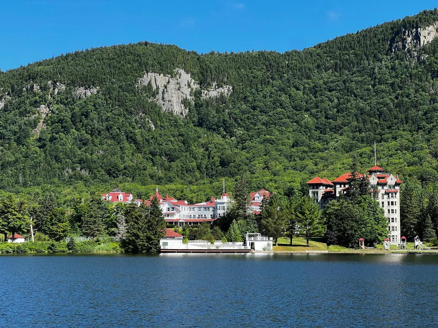 Charming view of scenic Grand Hotel amidst lush greenery and serene lake in White Mountains.