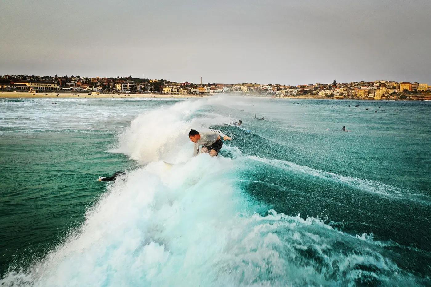 A surfer skillfully rides a wave at the iconic Bondi Beach, perfect for sports and travel imagery.