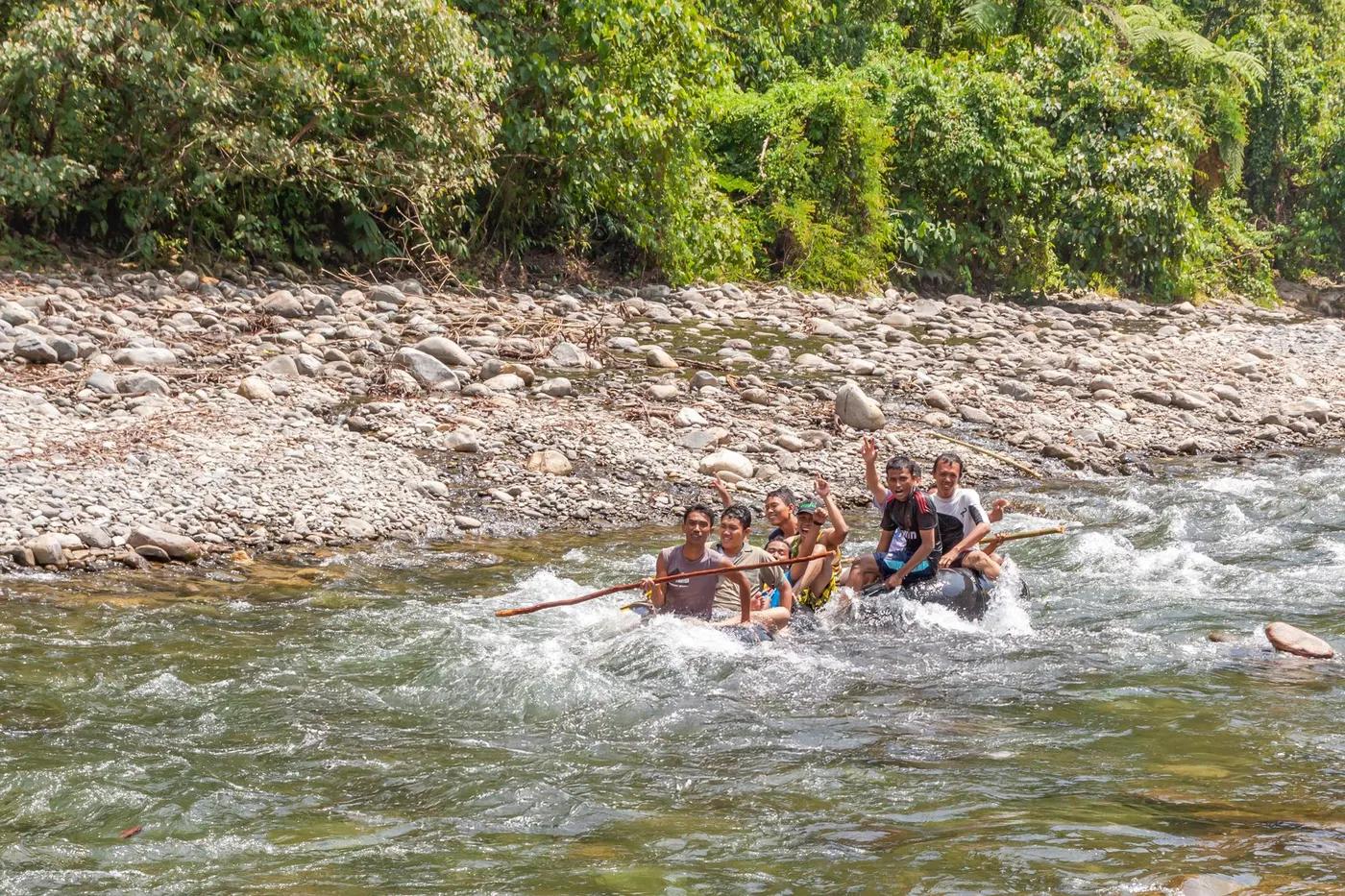 A lively group enjoying rafting on a rocky river amidst lush greenery, capturing outdoor adventure.